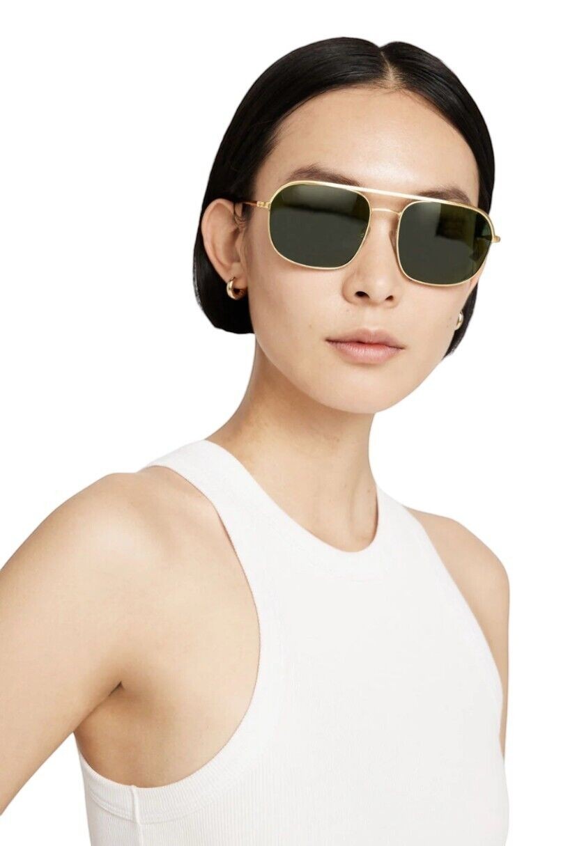 Naked Pear model wearing Karen Walker Pampel aviator sunglasses with gold frames and grass-green lenses.