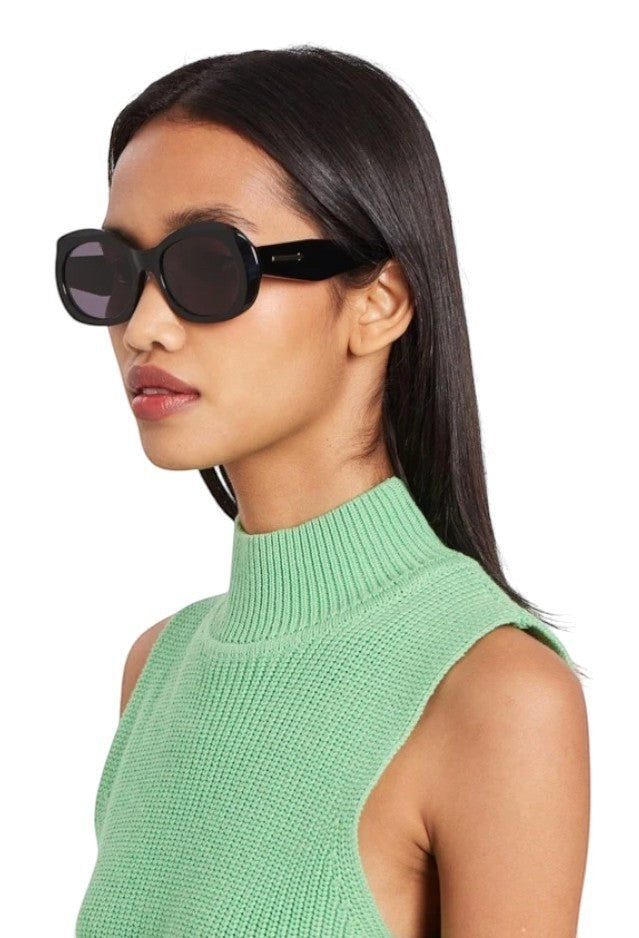 Model wearing Naked Pear Karen Walker Parlour B oversized black oval acetate sunglasses with smoke lenses