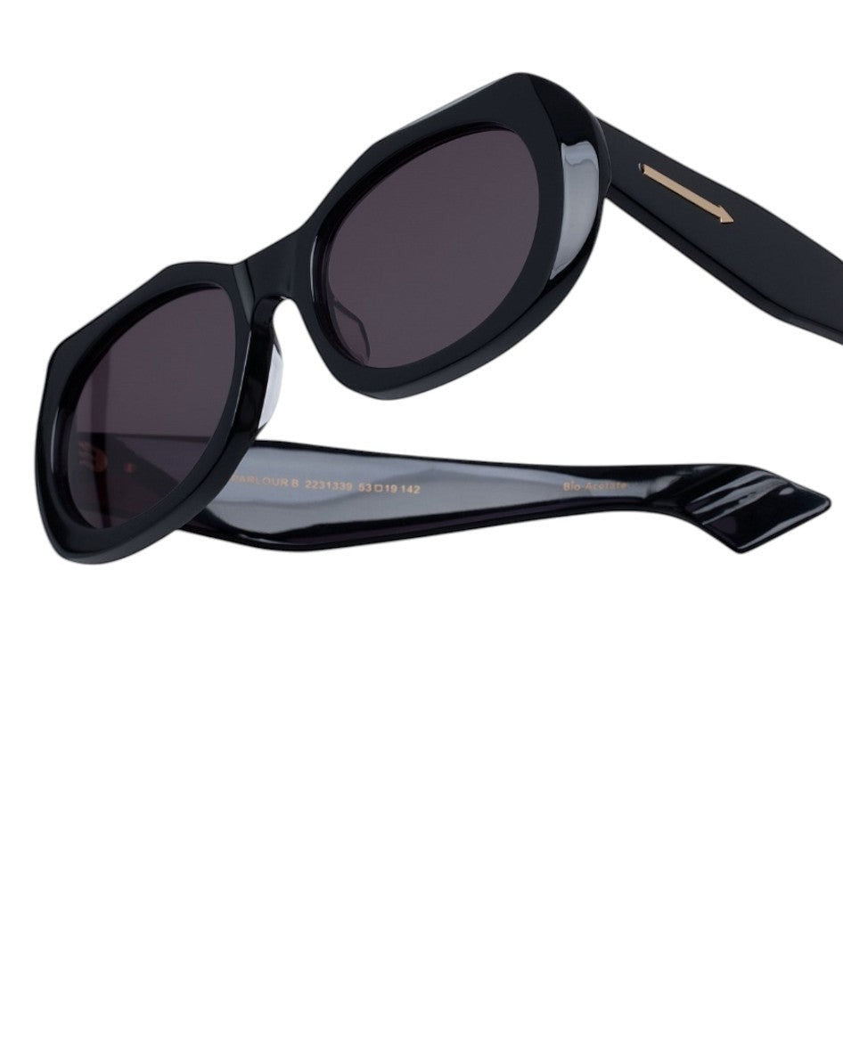 Naked Pear Karen Walker Parlour B black acetate oval sunglasses with smoke lenses and iconic arrow temple branding.