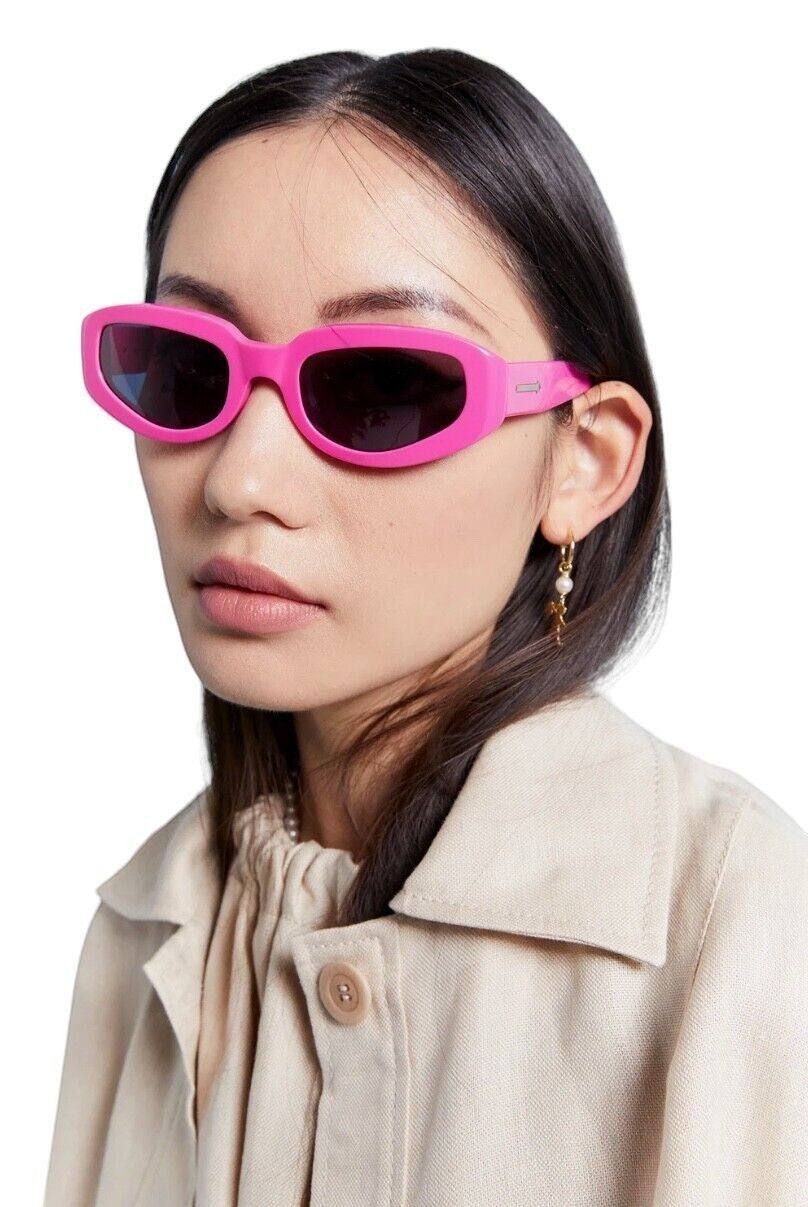 Model wearing Naked Pear Karen Walker Rally sunglasses in bright fuchsia pink acetate with smoke grey mono lenses.