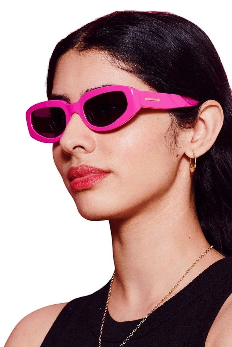 Model wearing Naked Pear Karen Walker Rally sunglasses in bright fuchsia pink acetate with grey mono lenses.