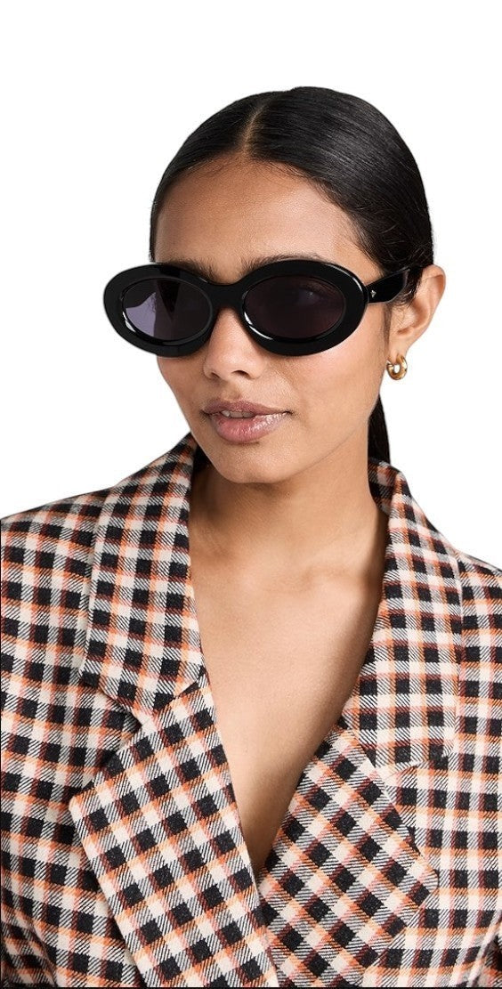 Model wearing Naked Pear Karen Walker Rapture B oval black bio-acetate sunglasses with grey lenses