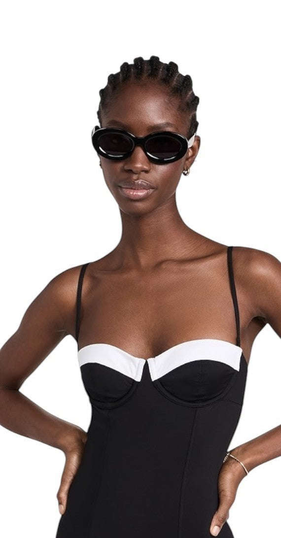 Naked Pear model wearing black oval Karen Walker Rapture B sunglasses with grey lenses and gold arrowhead detail