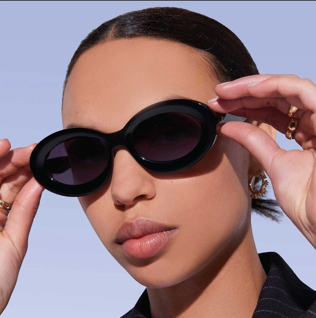 Model wearing Naked Pear Karen Walker Rapture B black oval bio-acetate sunglasses with grey lenses