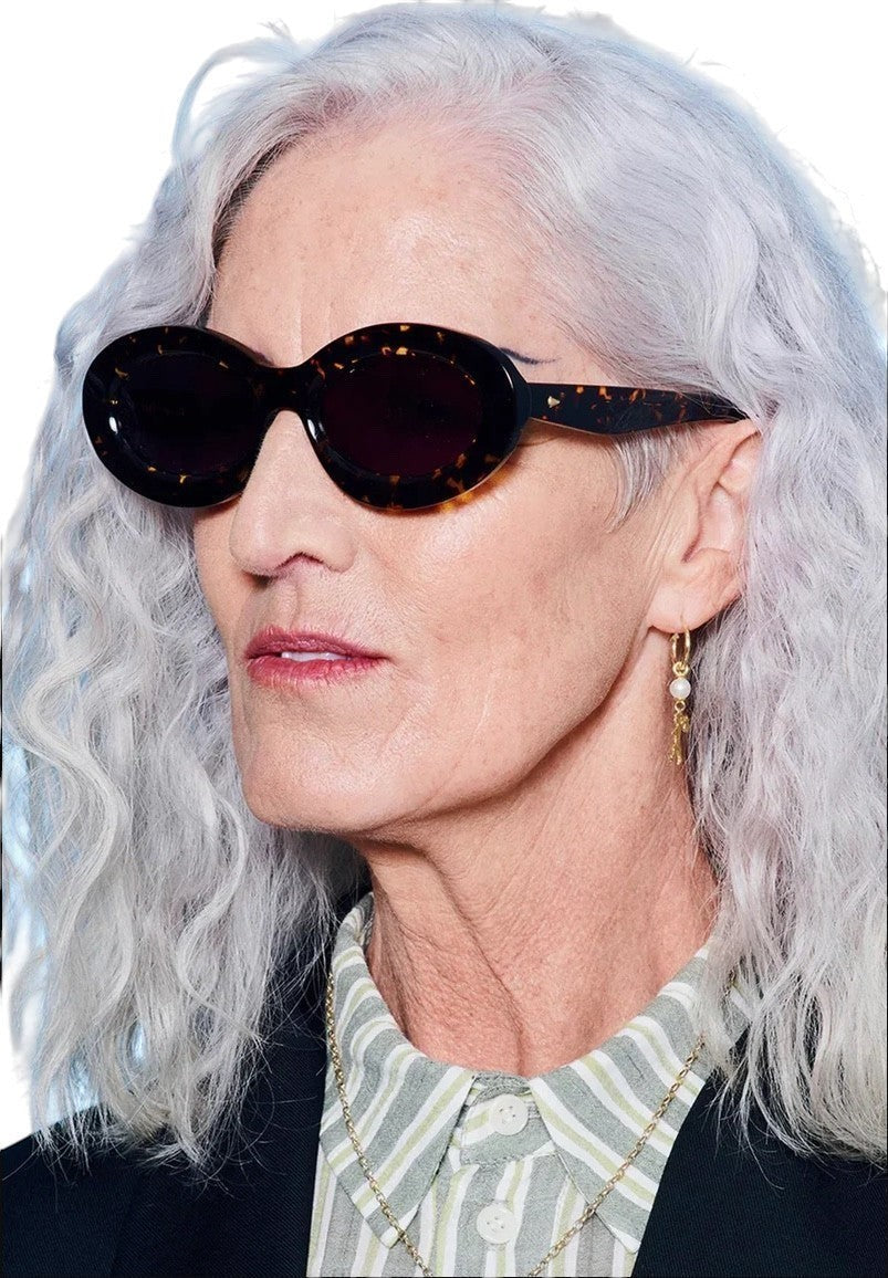 Model wearing Naked Pear Karen Walker Rapture B oval sunglasses in cracked tortoise shell bio-acetate with grey lenses.