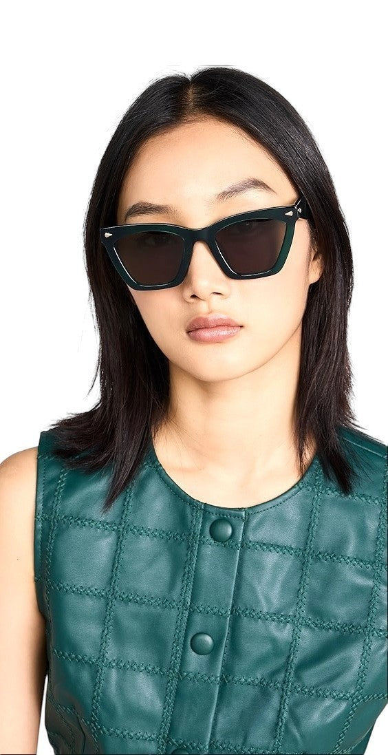 Model wearing Naked Pear Karen Walker Spellbound emerald green cat-eye acetate sunglasses with gold arrow hardware.