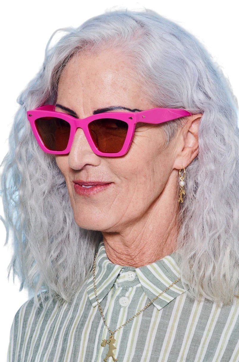 Naked Pear Karen Walker Spellbound cat-eye sunglasses in fuchsia acetate with brown lenses worn by a woman