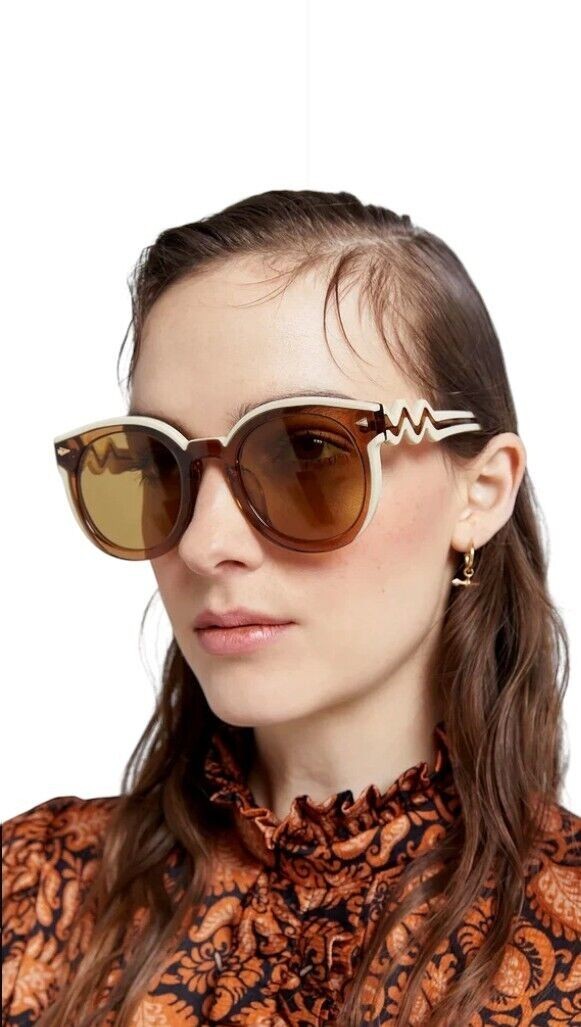 Model wearing Naked Pear Karen Walker Super Wavy Duper sunglasses with ochre tan and cream round frames and wavy arms.