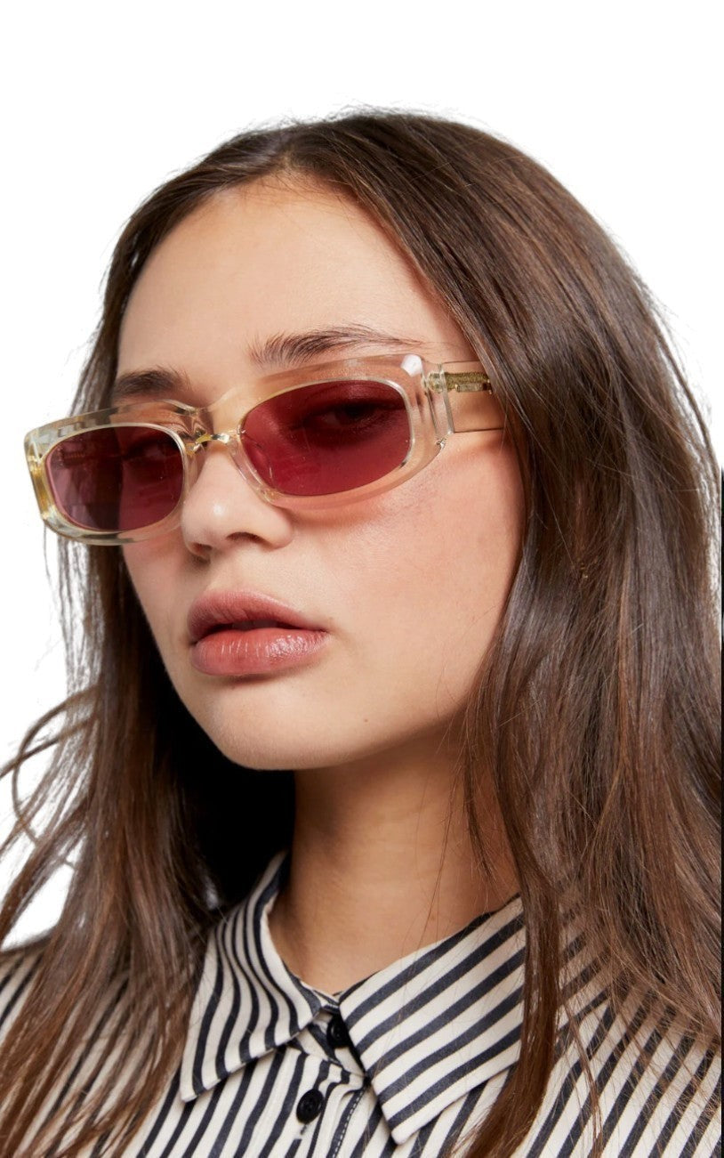 Model wearing Naked Pear Karen Walker Zahra B rectangle sunglasses with vintage clear frames and dusty pink lenses.