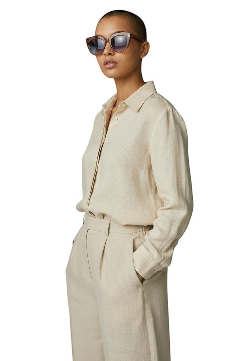 Naked Pear Le Specs Air Heart cat eye sunglasses in smokey pink worn by a model in a beige linen shirt and trousers