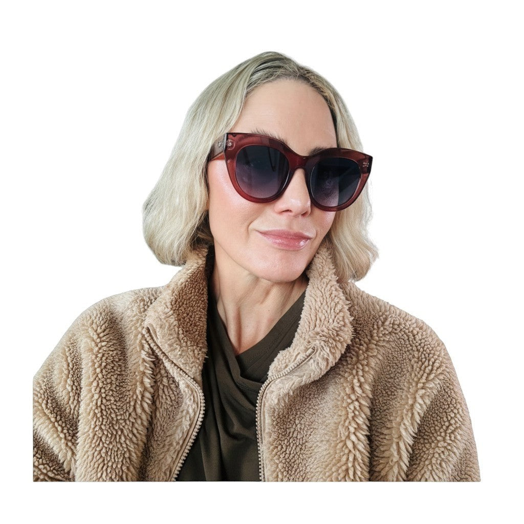 Naked Pear Le Specs Air Heart cat eye sunglasses in smokey pink worn by a woman in a tan fleece jacket