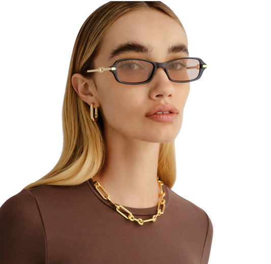 Woman wearing glasses and a gold necklace on a white background