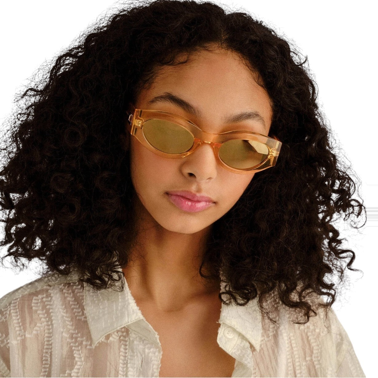 Woman wearing gold sunglasses with a neutral background