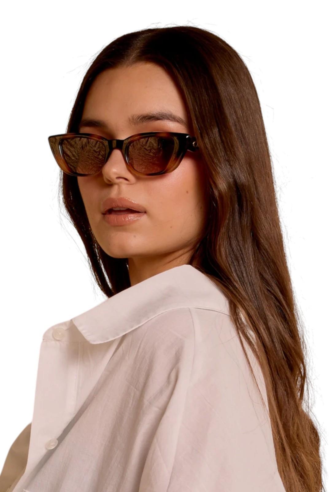 Woman wearing cat-eye sunglasses with a neutral background