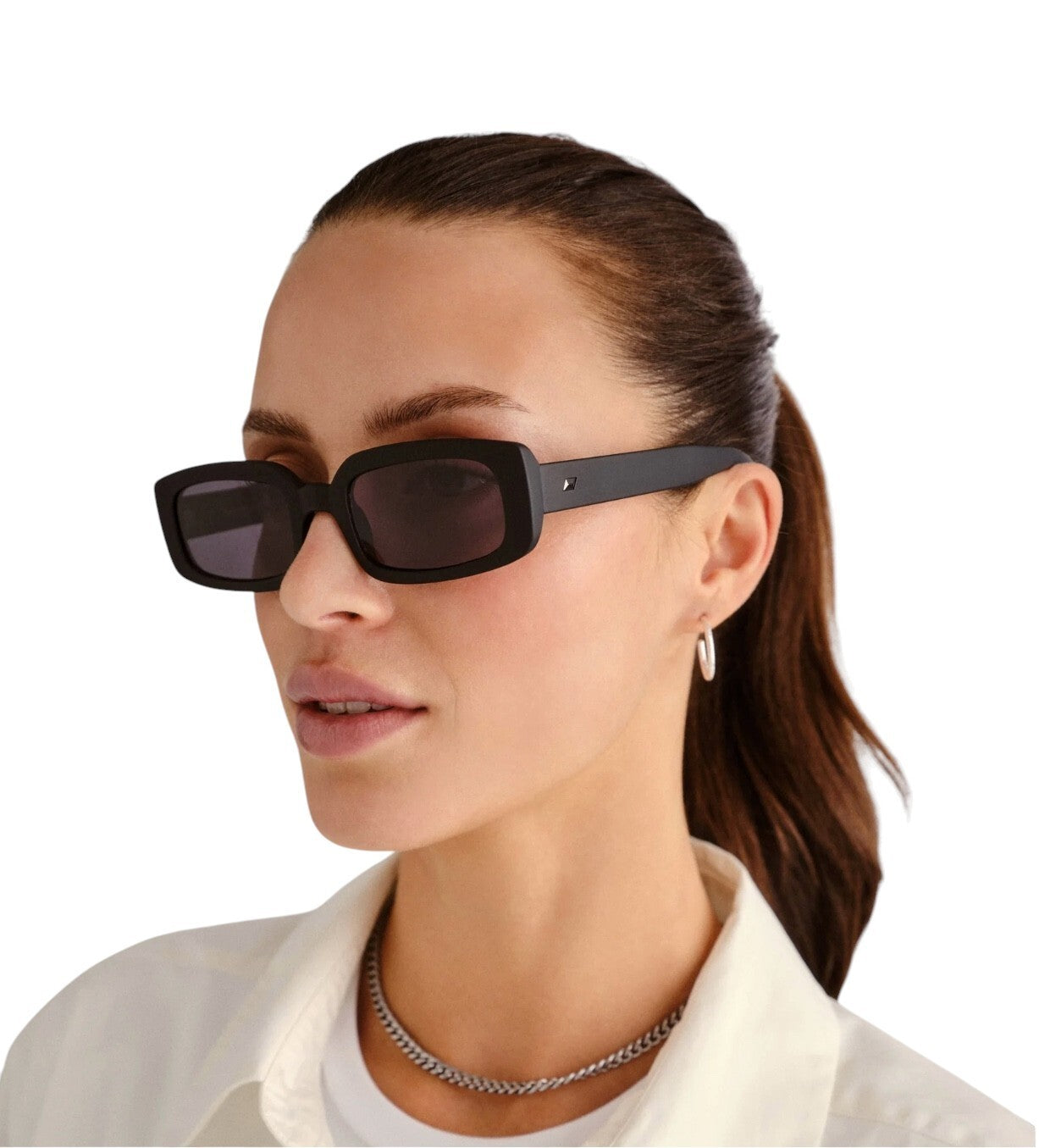 Woman wearing dark sunglasses with a plain background