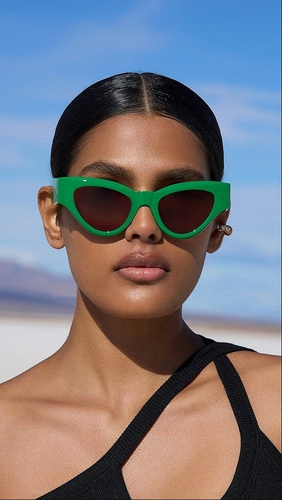 Person wearing green sunglasses with a clear blue sky background
