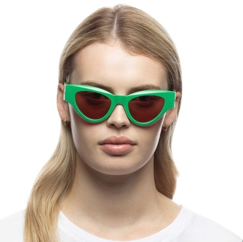 Woman wearing green sunglasses with a plain background