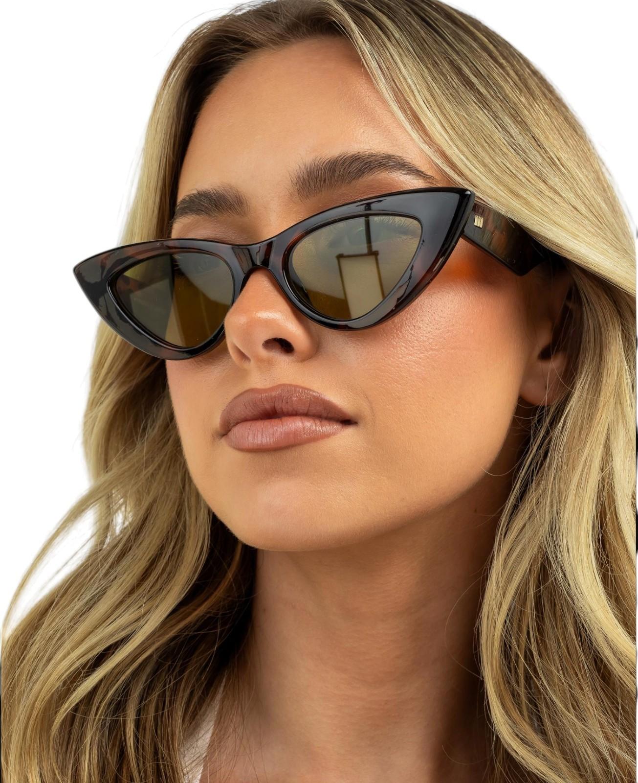 Woman wearing cat-eye sunglasses with a neutral background