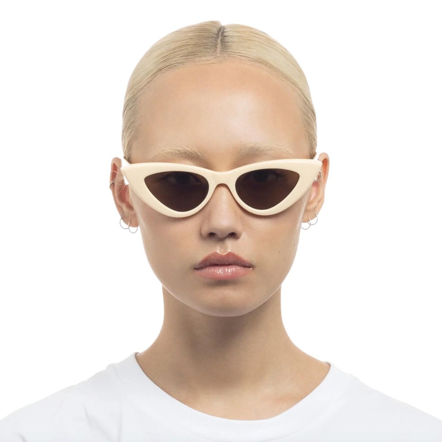 Person wearing beige cat-eye sunglasses on a white background