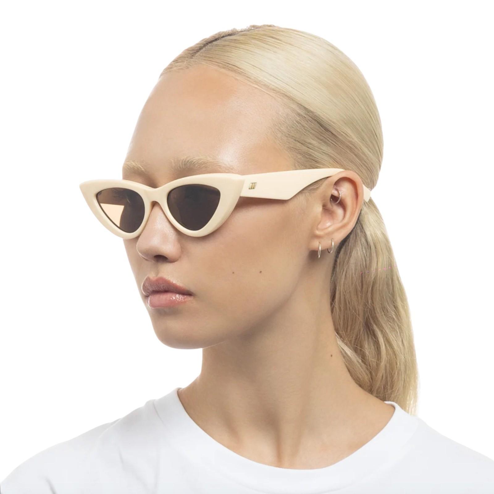 Woman wearing beige cat-eye sunglasses on a white background
