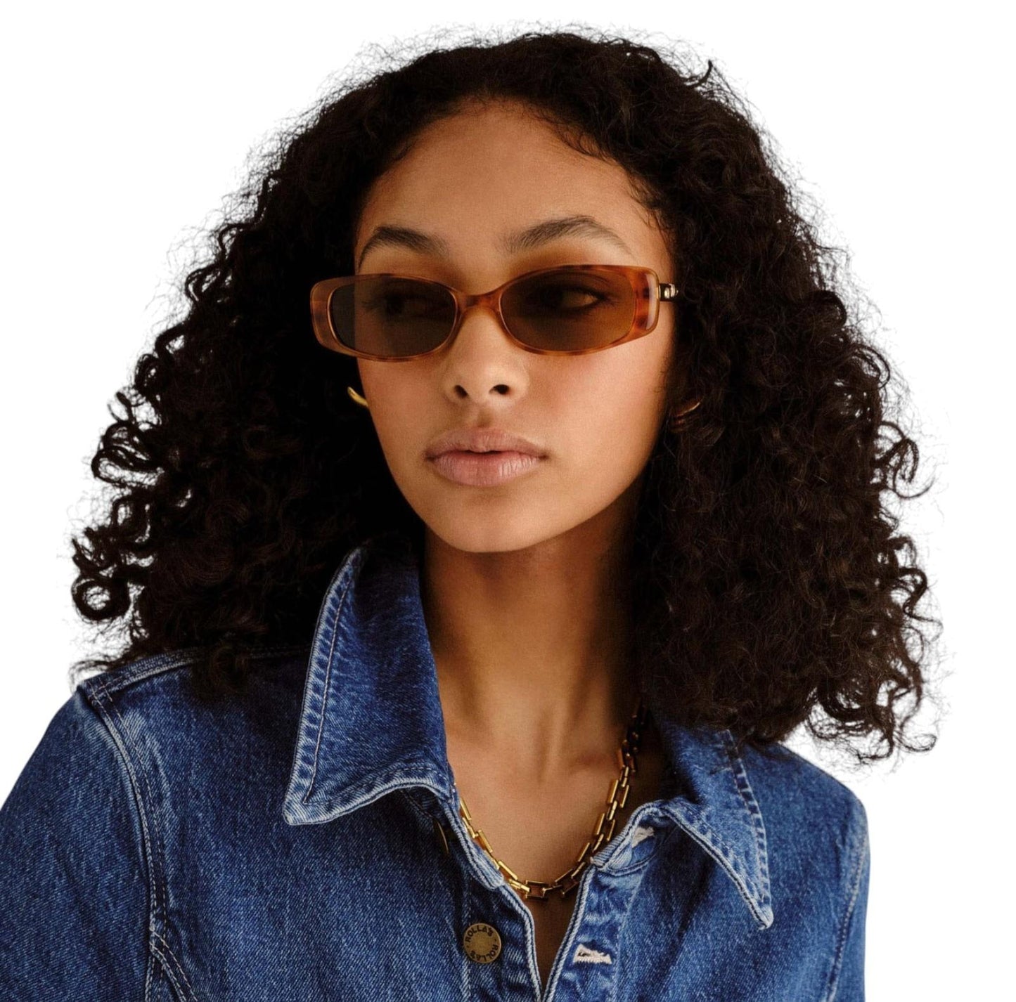 Woman wearing sunglasses and a denim jacket on a white background