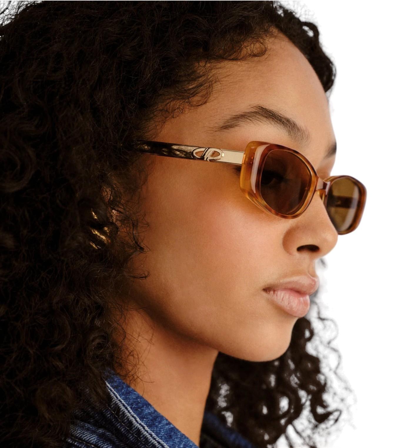 Close-up of a person wearing sunglasses with a neutral background