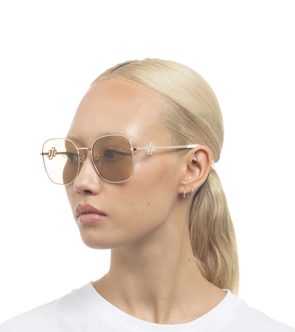 Woman wearing gold-framed sunglasses with a plain white background
