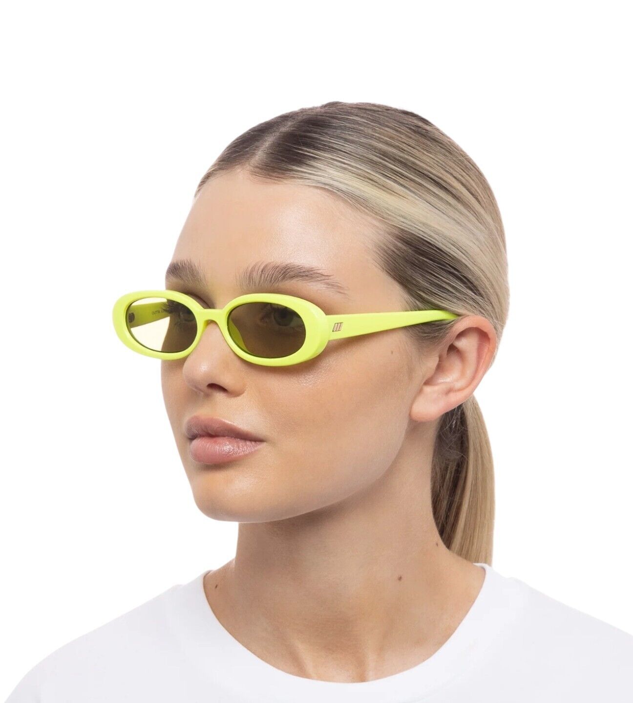 A person wearing neon yellow/green oval sunglasses with a small frame and 90's style.