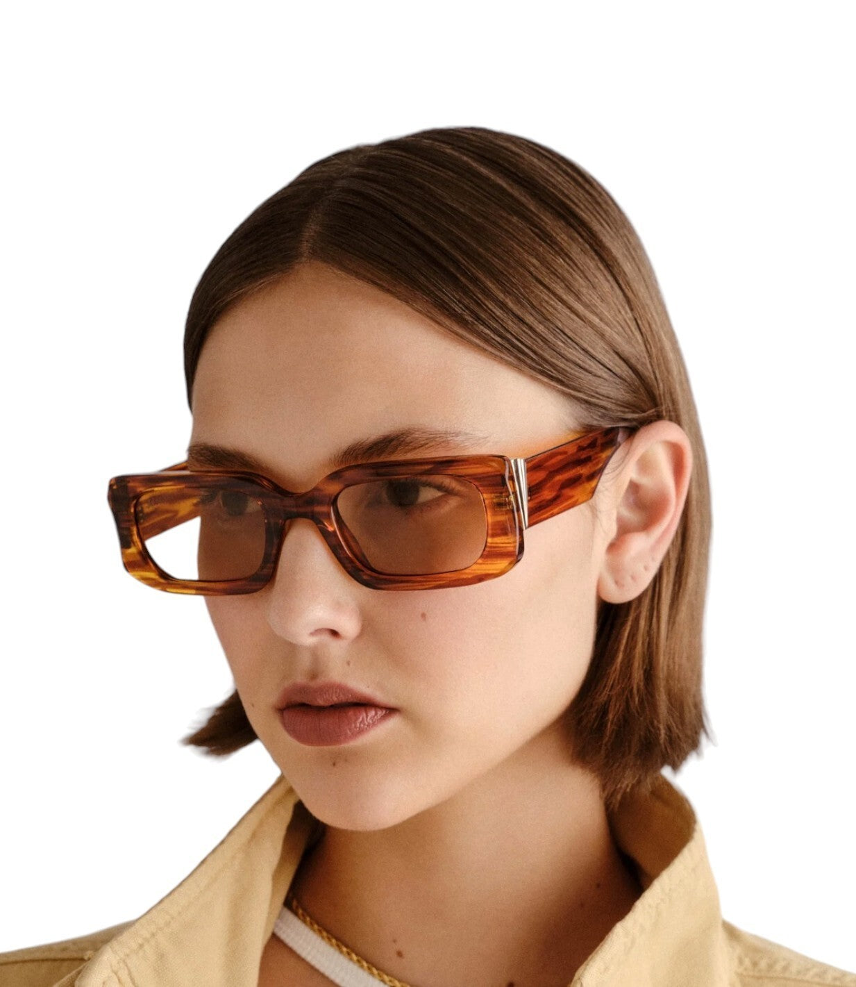 Person wearing a pair of tortoiseshell sunglasses with a neutral background