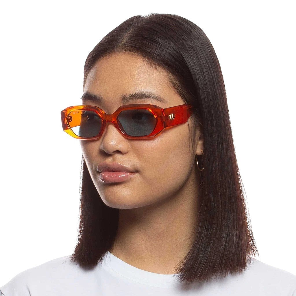 Person wearing orange sunglasses with a plain background