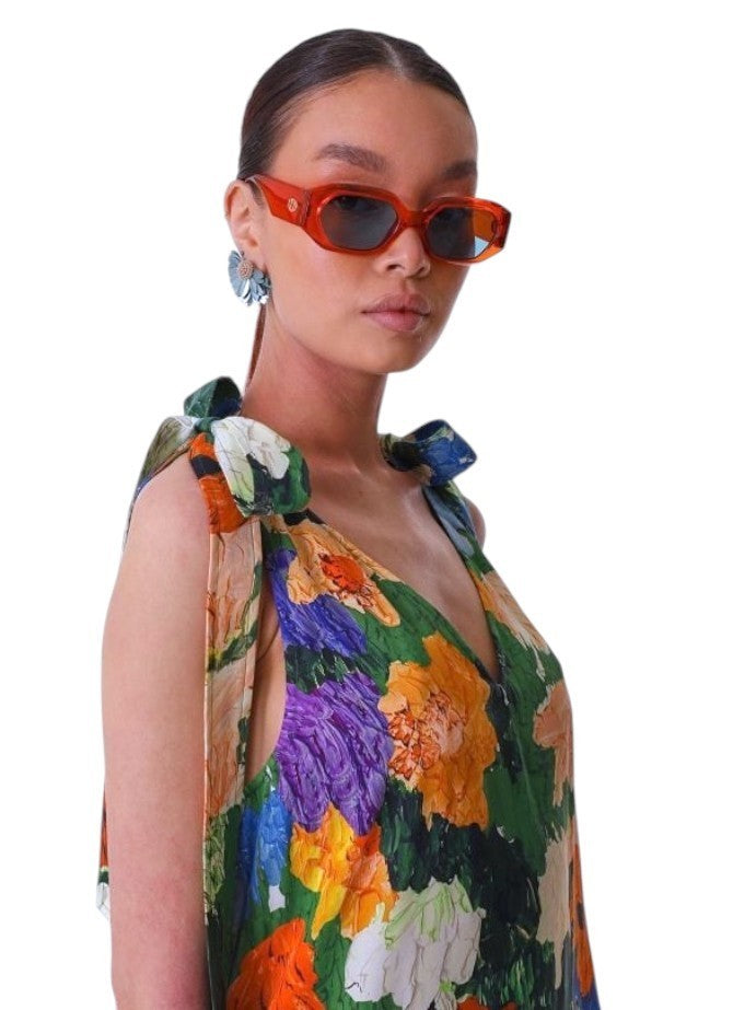 Woman wearing a colorful floral dress and sunglasses on a white background