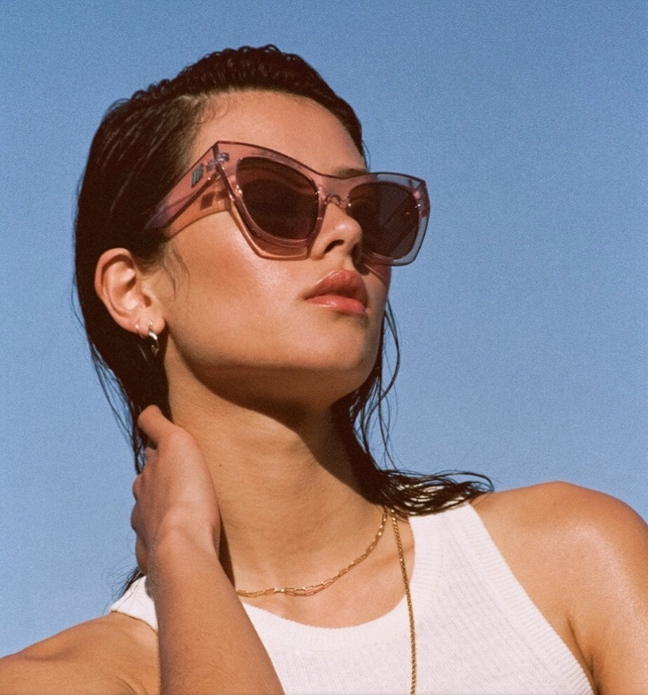 Woman wearing pink sunglasses against a clear blue sky