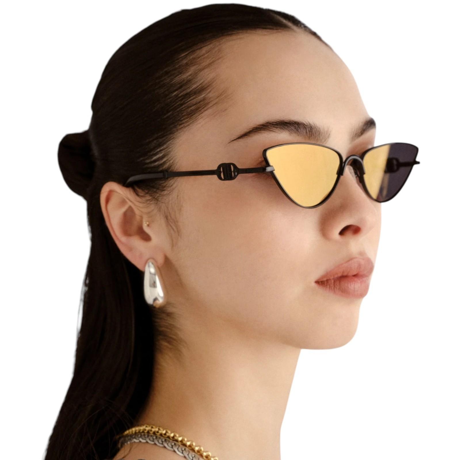 Woman wearing cat-eye sunglasses with a plain background