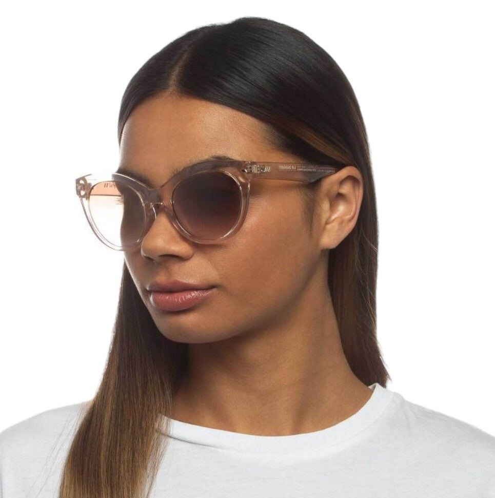 Woman wearing clear sunglasses with a plain background