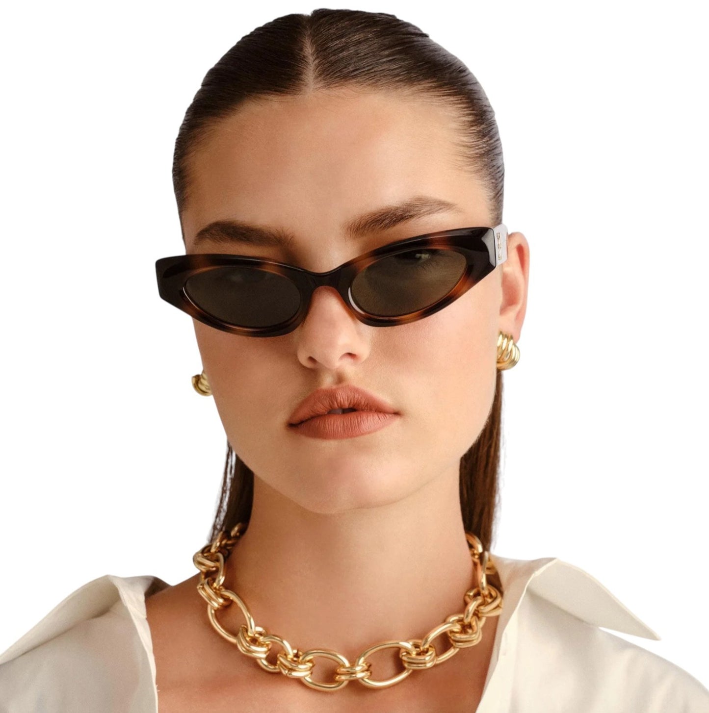 Woman wearing tortoiseshell sunglasses and a gold chain necklace on a white background