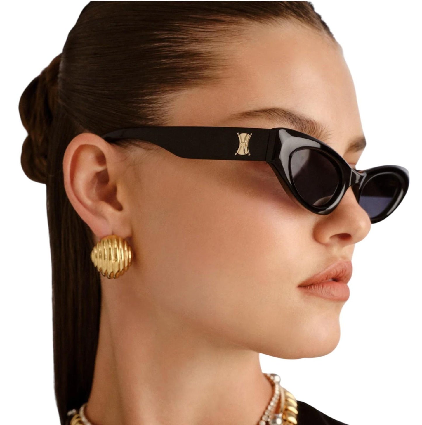 Woman wearing black sunglasses with a gold logo and gold earrings on a white background
