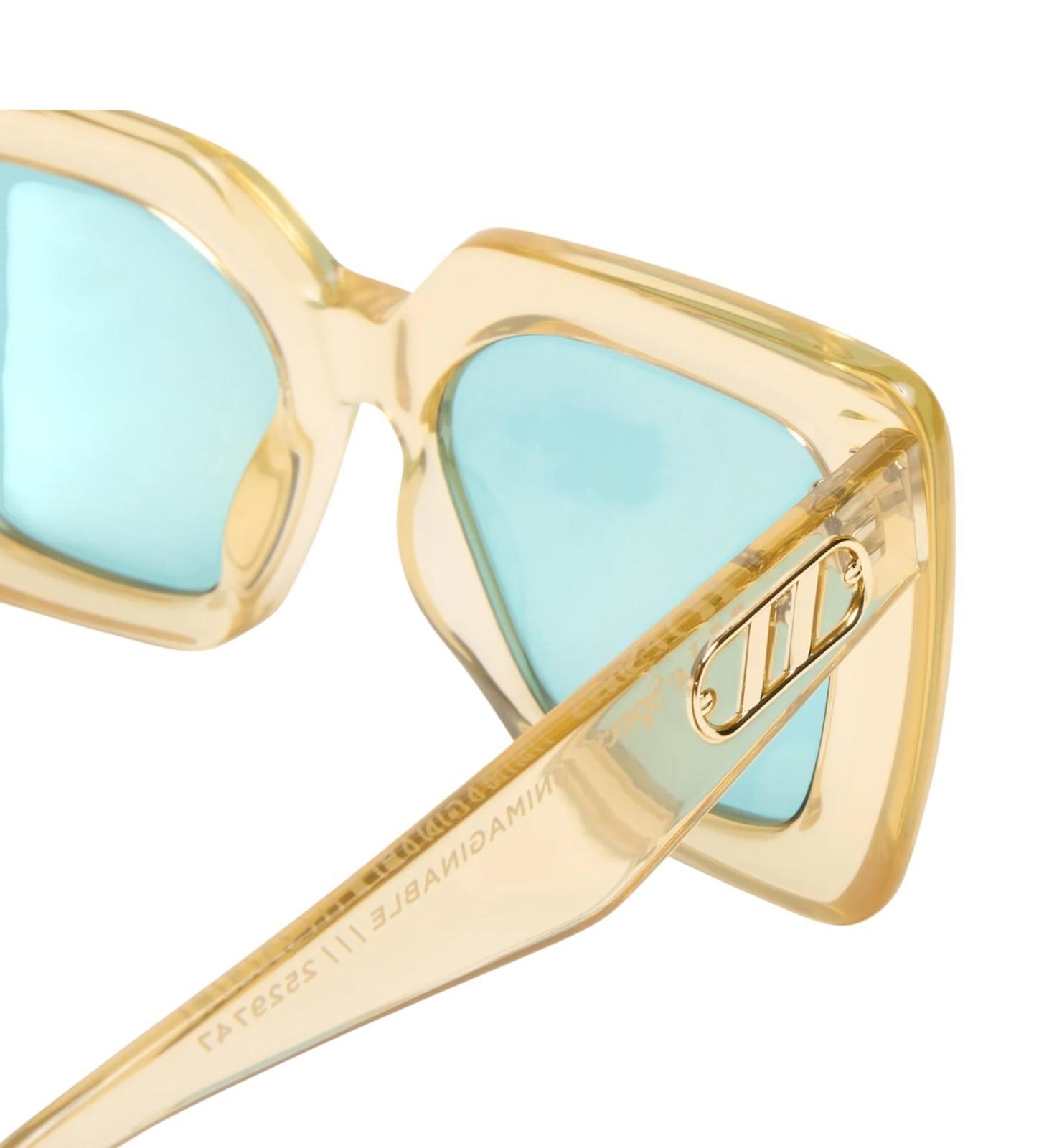 Gold-framed sunglasses with light blue lenses on a white background