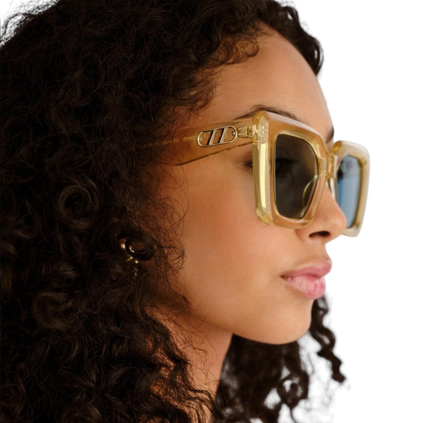 Woman wearing gold sunglasses with a neutral background