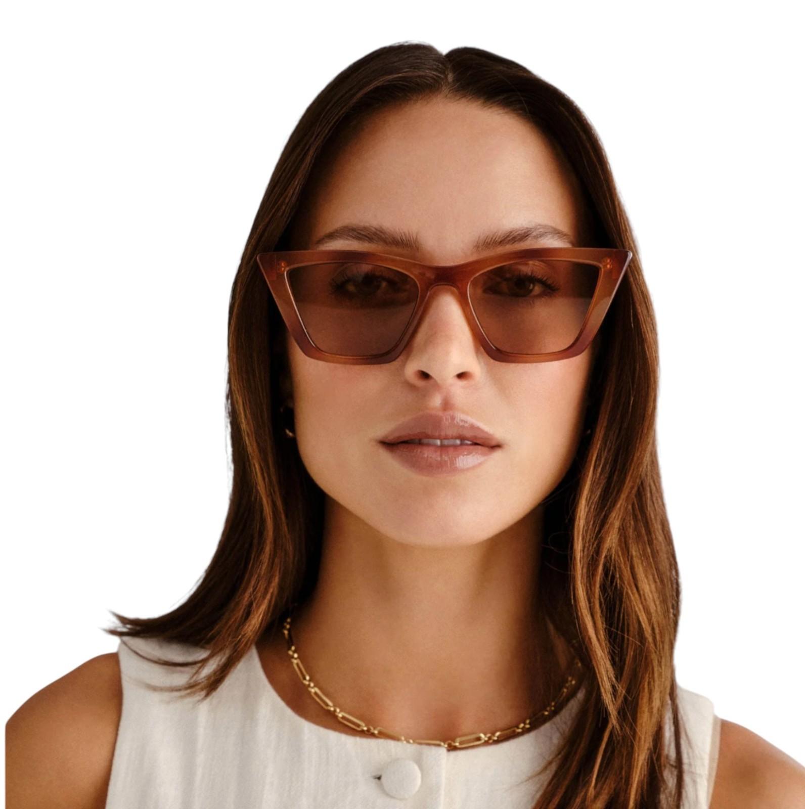 Woman wearing brown cat-eye sunglasses on a white background