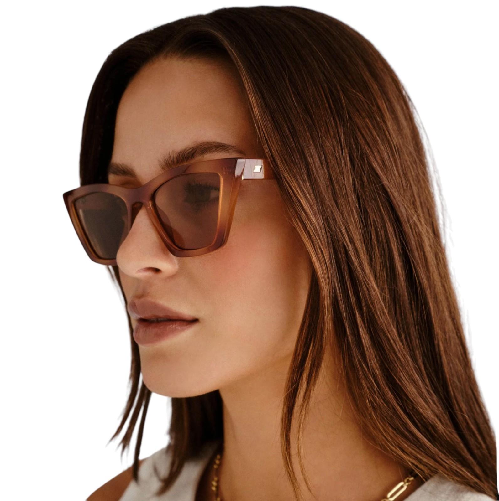 Woman wearing brown sunglasses with a neutral background