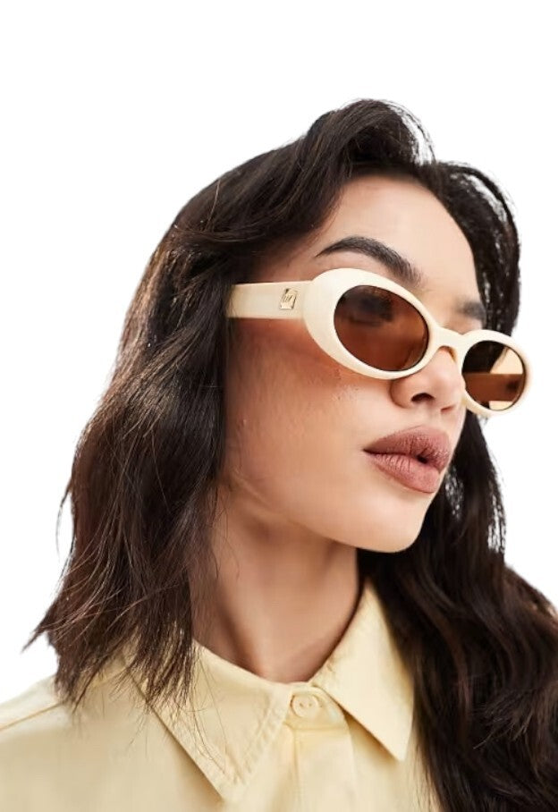 Woman wearing gold sunglasses with a white background