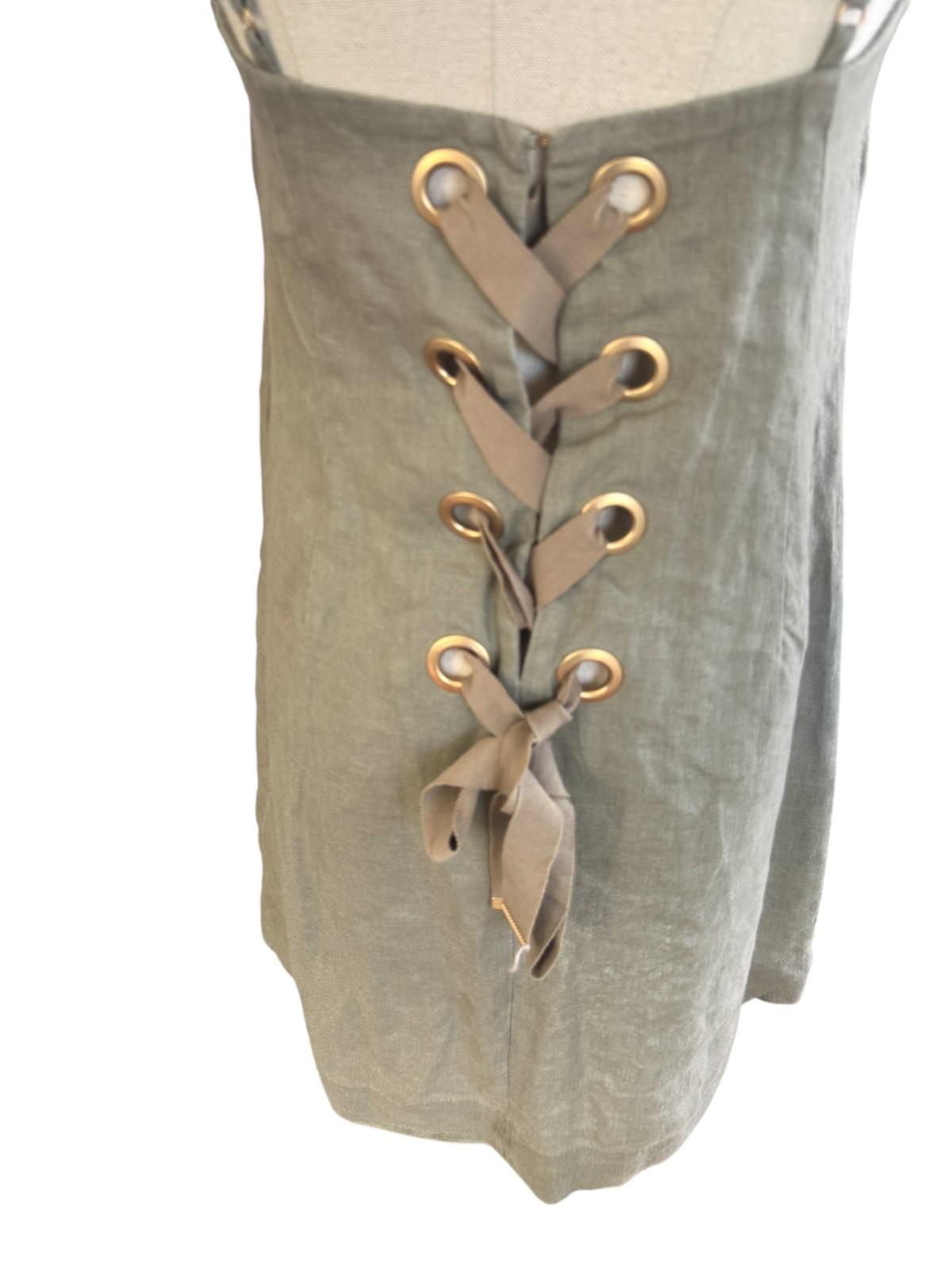 Green pants with gold lace-up details on a mannequin against a white background