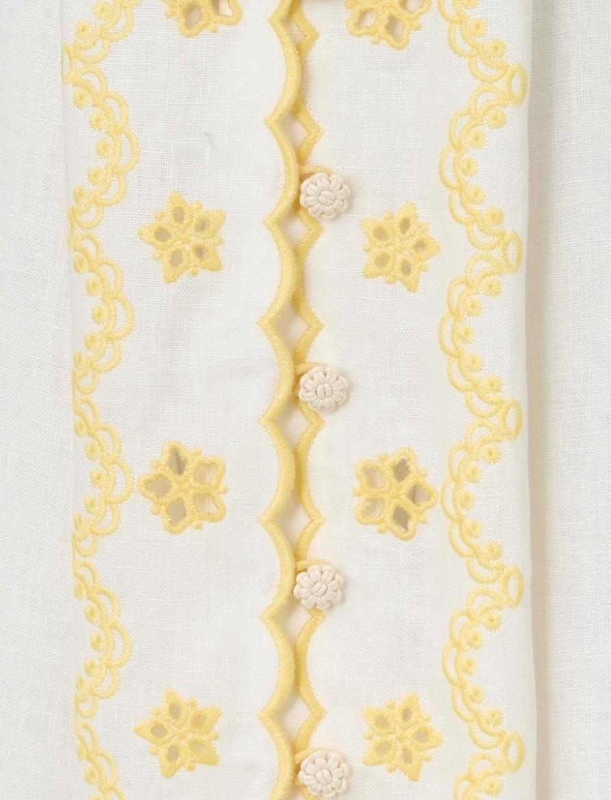 AI generated image of Naked Pear Zimmermann linen midi dress detail featuring ivory fabric with yellow floral embroidery and crochet buttons