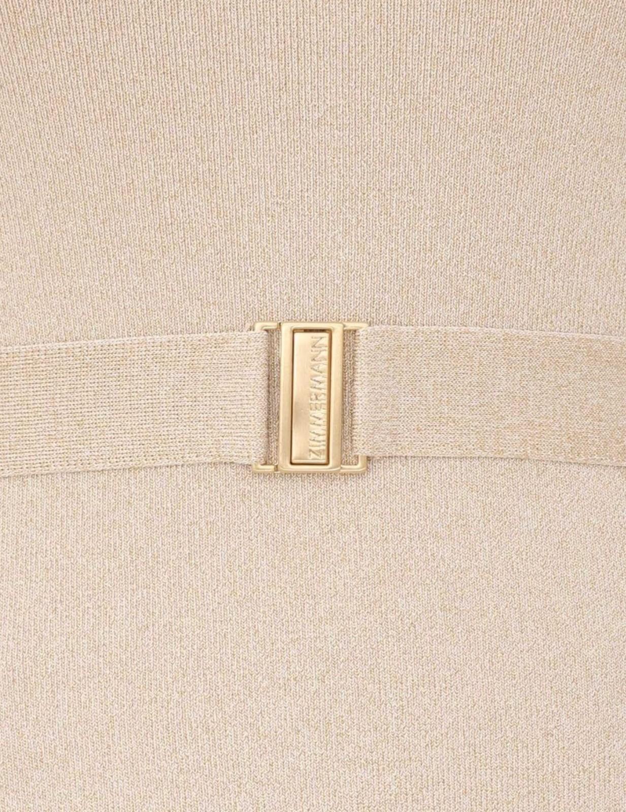 Close-up of a beige fabric with a gold buckle on a matching beige background