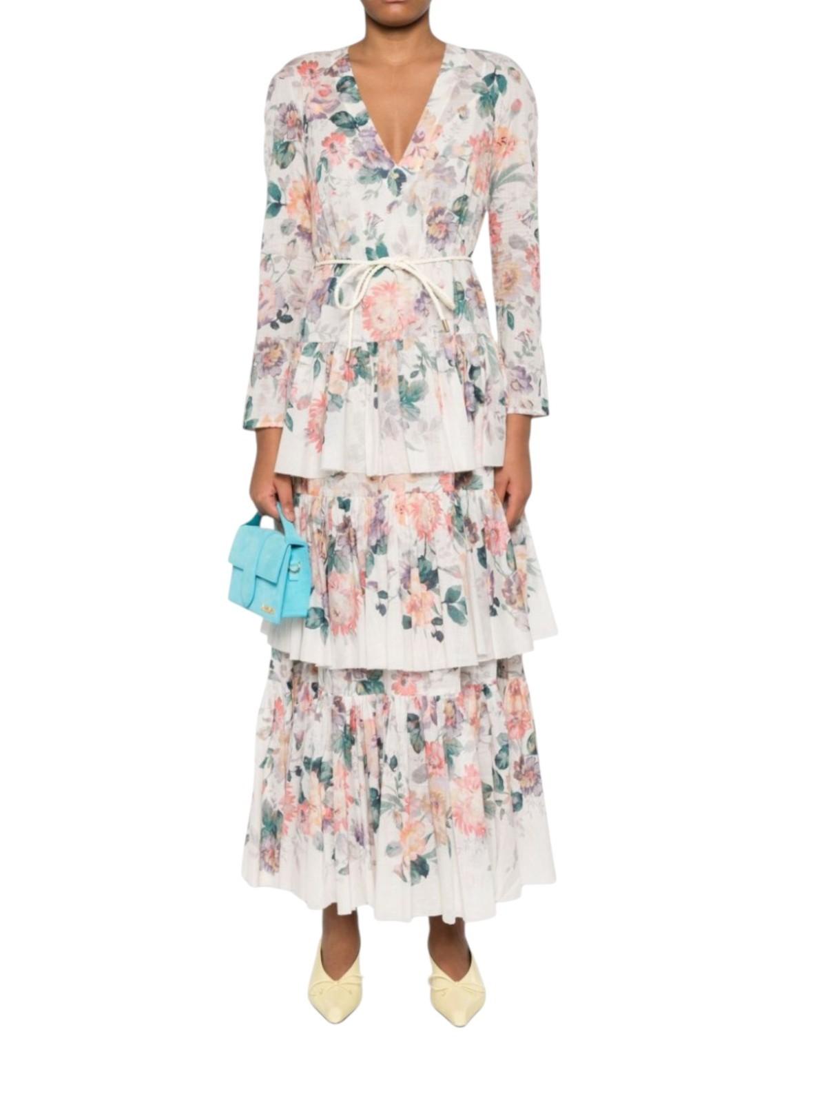 Woman wearing a floral dress holding a blue clutch on a white background