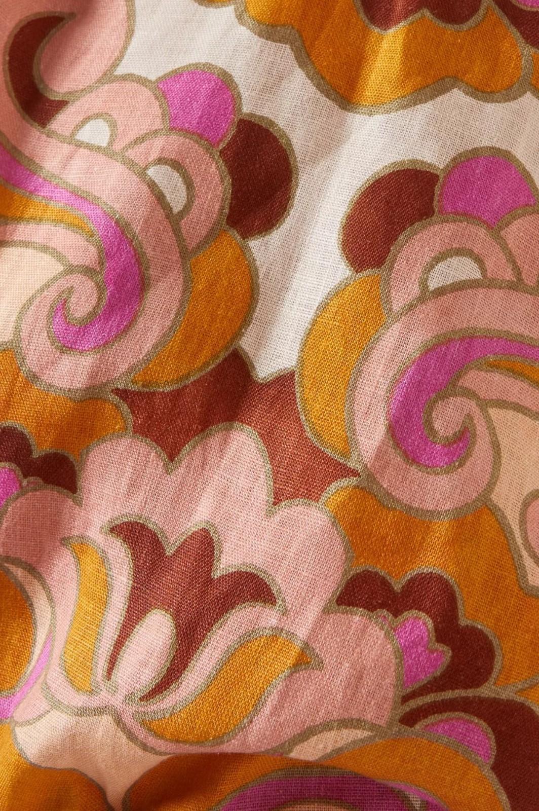 Close-up of a fabric with a floral pattern in pink, orange, and brown.