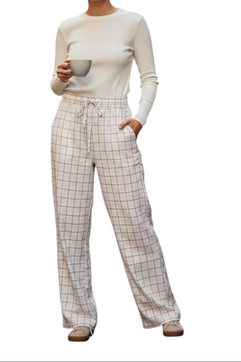AI generated image of Person wearing a white long-sleeve top and plaid pants holding a mug on a white background