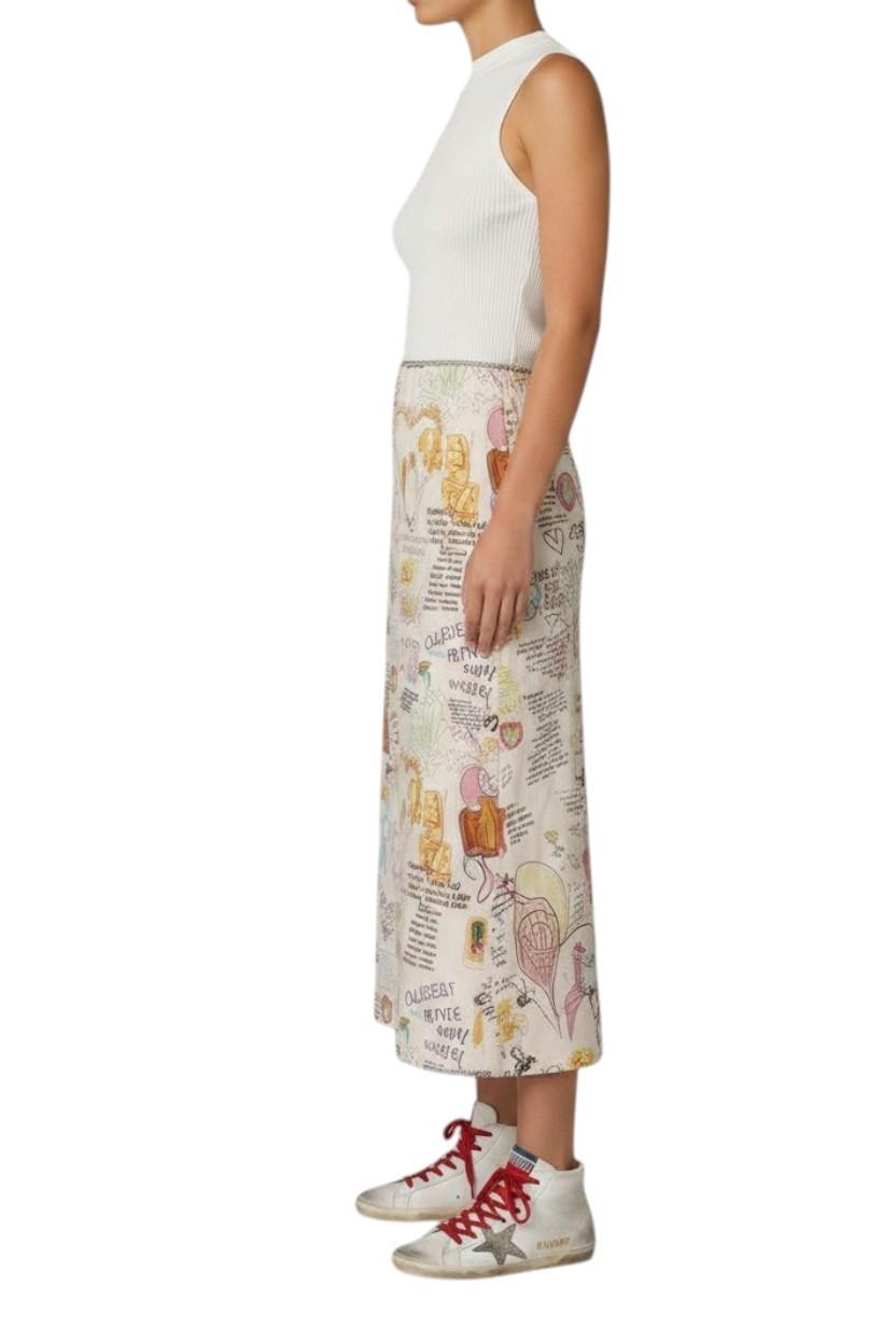 Person wearing a patterned skirt with a white top and sneakers on a white background