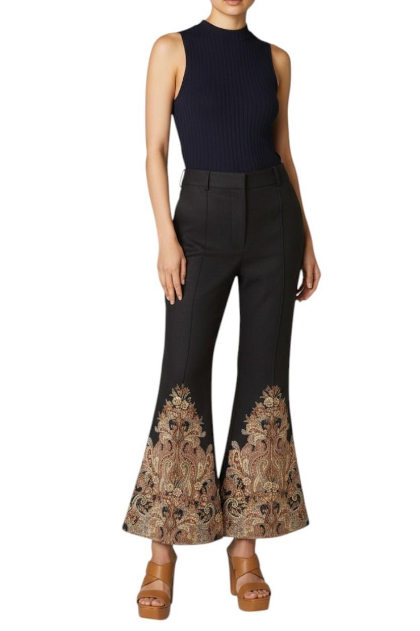 AI generated image of Woman wearing a sleeveless navy top and black flared pants with floral embroidery on a white background