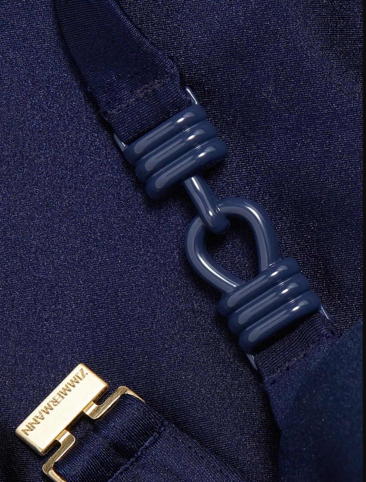 Close-up of a navy blue bikini bottoms with a gold tag on a matching fabric background
